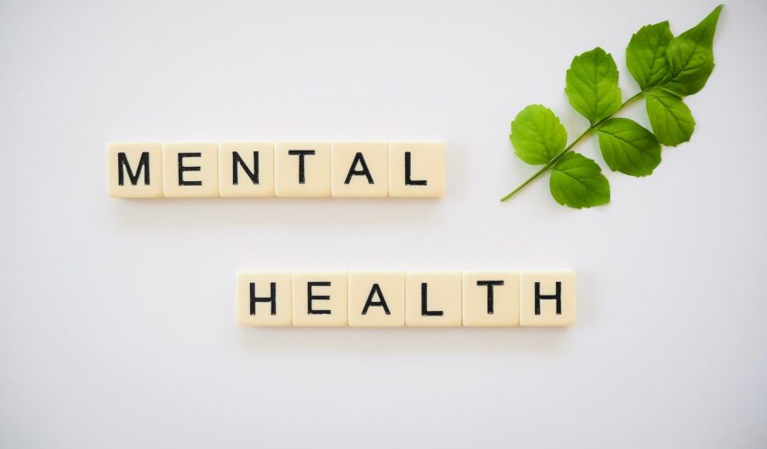 the word mental health spelled with scrabbles next to a green leaf